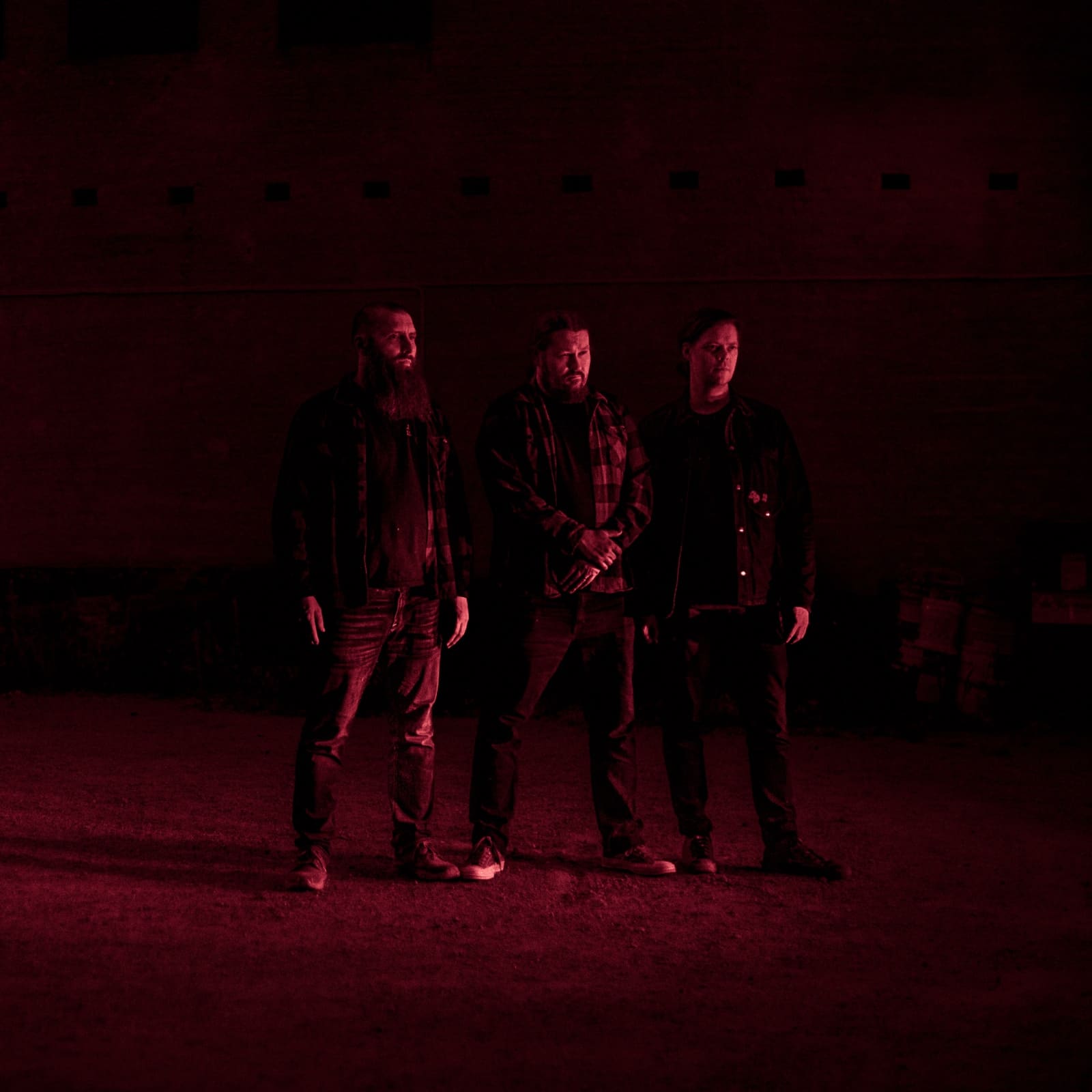 Band members illuminated by and looking towards a mysterious red light